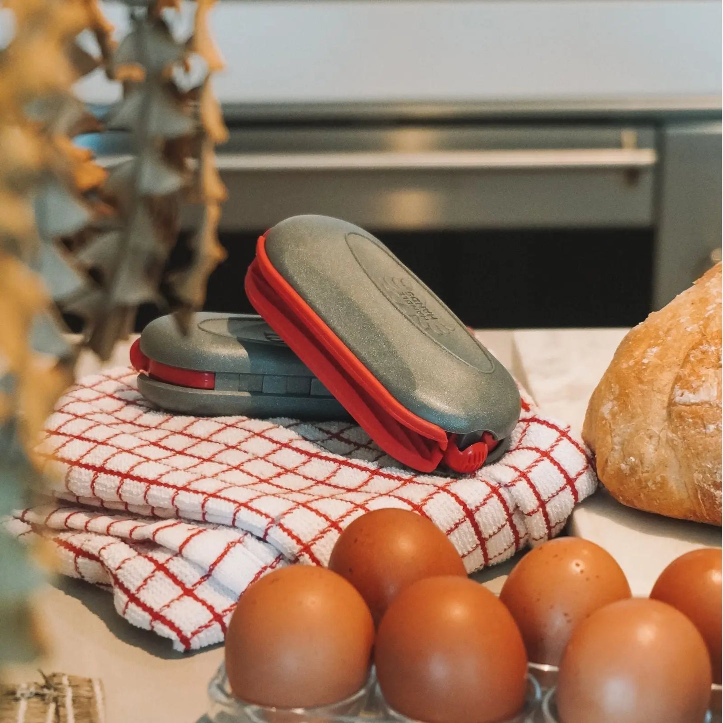 a set of 2 red pebblegrips on kitchen counter top between bread and eggs